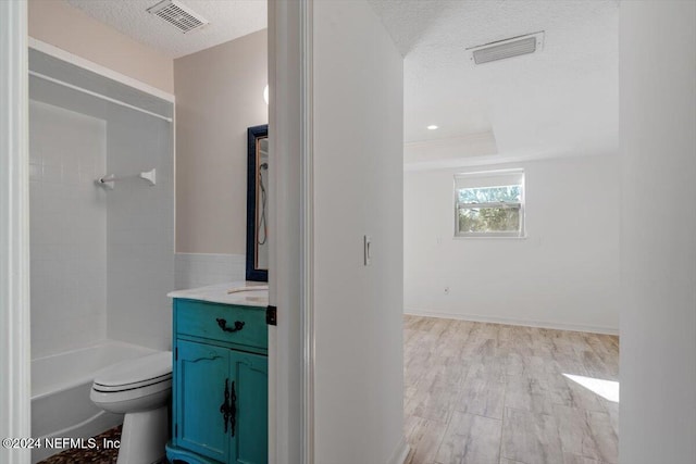 full bathroom featuring tiled shower / bath combo, vanity, a textured ceiling, and toilet