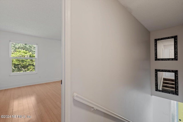 hall featuring wood-type flooring and a textured ceiling