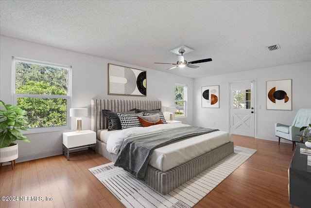 bedroom with a textured ceiling, hardwood / wood-style floors, and ceiling fan