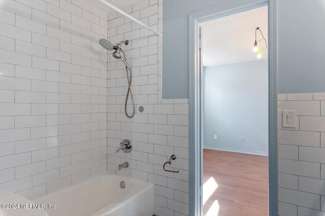 bathroom with hardwood / wood-style flooring and tiled shower / bath combo