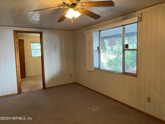 unfurnished room featuring light carpet, a textured ceiling, and ceiling fan