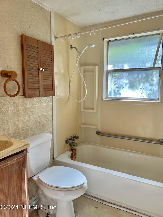 full bathroom with washtub / shower combination, a textured ceiling, toilet, tile walls, and vanity