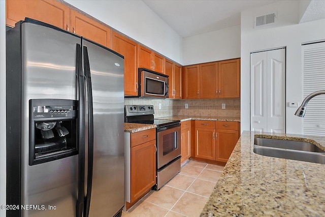 kitchen with light tile patterned flooring, stainless steel appliances, sink, and light stone counters