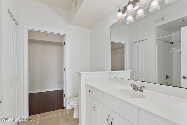 bathroom with a tile shower, a textured ceiling, toilet, vanity, and tile patterned flooring