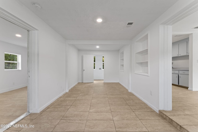 corridor featuring built in features and light tile patterned flooring