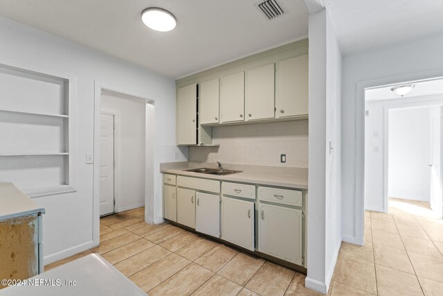 kitchen featuring light tile patterned floors, built in features, sink, and backsplash