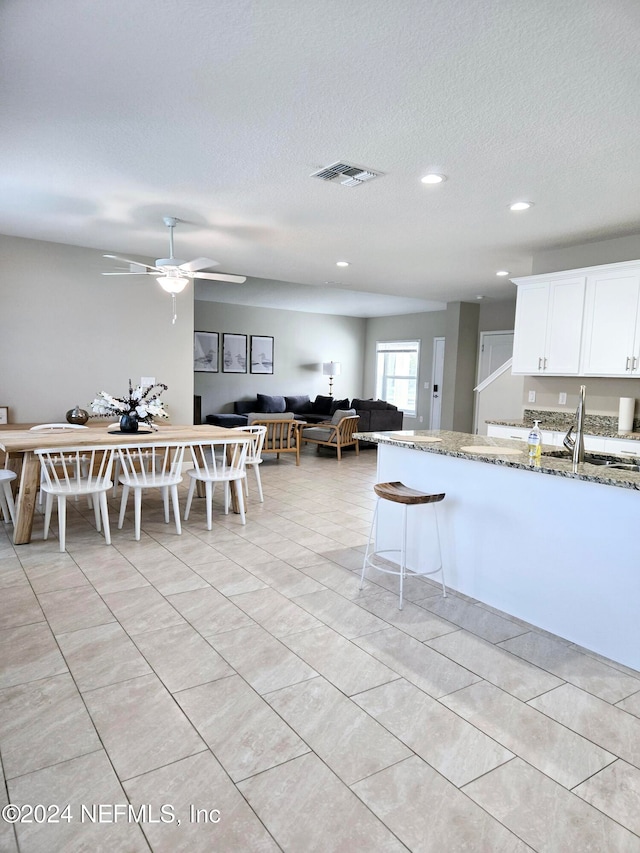 kitchen with white cabinets, sink, light tile patterned flooring, ceiling fan, and light stone countertops