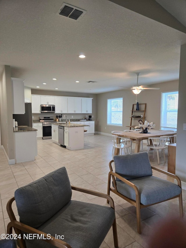 tiled living room with ceiling fan, plenty of natural light, sink, and a textured ceiling