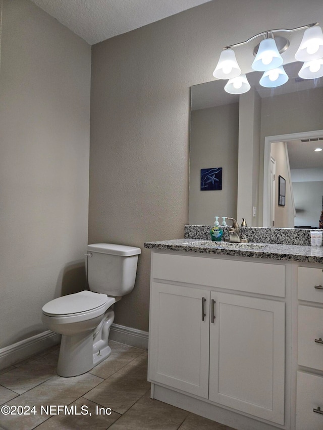 bathroom with toilet, vanity, a textured ceiling, and tile patterned flooring