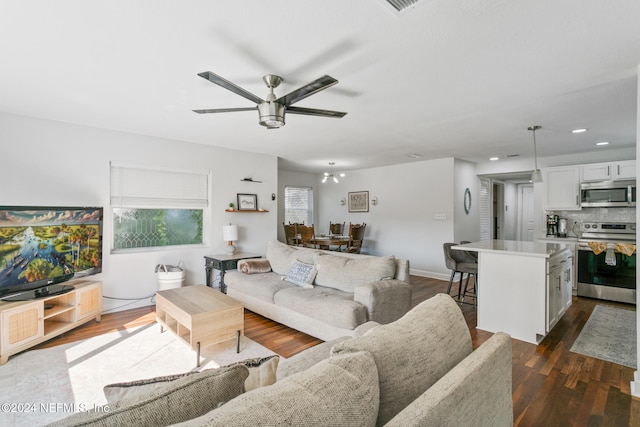 living room with dark hardwood / wood-style flooring and ceiling fan with notable chandelier