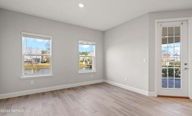 spare room with light wood-type flooring and a water view