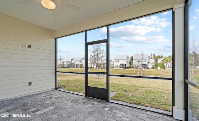 unfurnished sunroom featuring ceiling fan and a water view