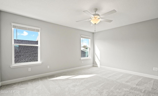 spare room featuring ceiling fan, light colored carpet, and a wealth of natural light