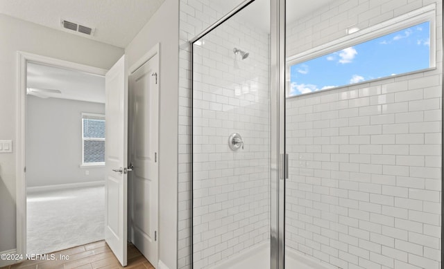 bathroom featuring a textured ceiling, ceiling fan, hardwood / wood-style floors, and an enclosed shower