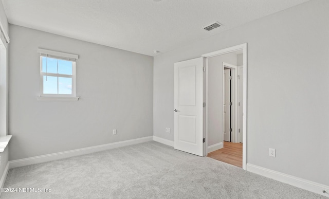 unfurnished bedroom featuring light colored carpet and a textured ceiling