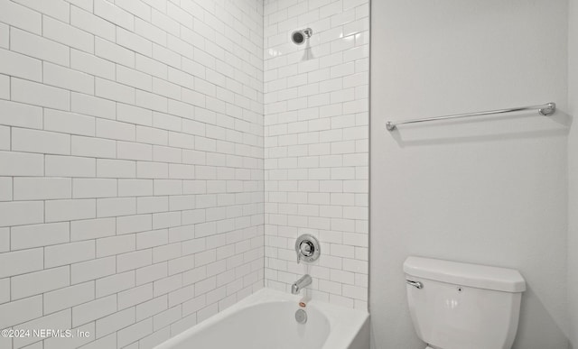 bathroom featuring tiled shower / bath combo and toilet