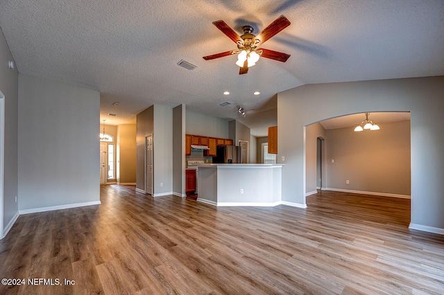 unfurnished living room with light hardwood / wood-style floors, a textured ceiling, vaulted ceiling, and ceiling fan with notable chandelier