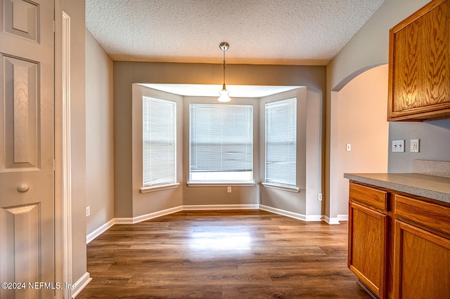 unfurnished dining area with dark hardwood / wood-style floors and a textured ceiling