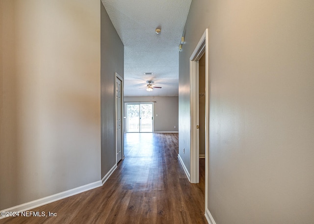 hall with a textured ceiling and dark hardwood / wood-style flooring