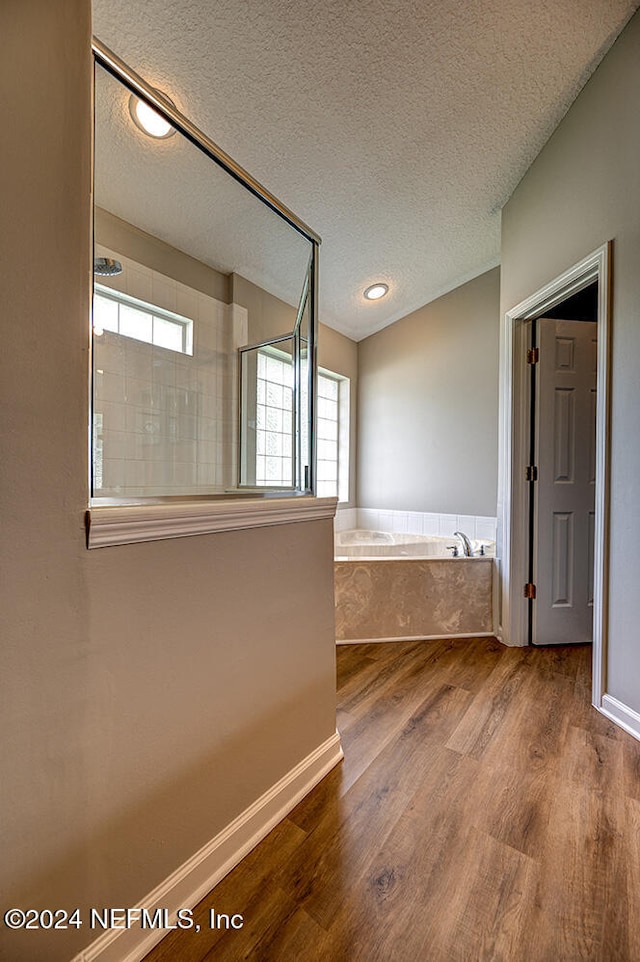 bathroom featuring wood-type flooring, a textured ceiling, and shower with separate bathtub