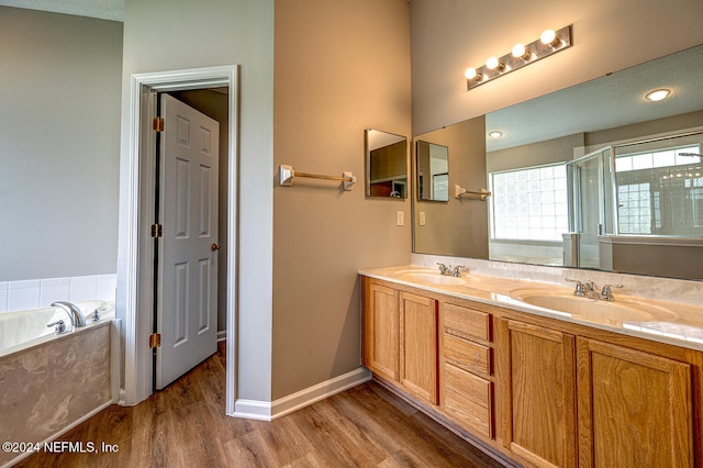 bathroom with vanity, a textured ceiling, hardwood / wood-style flooring, and plus walk in shower