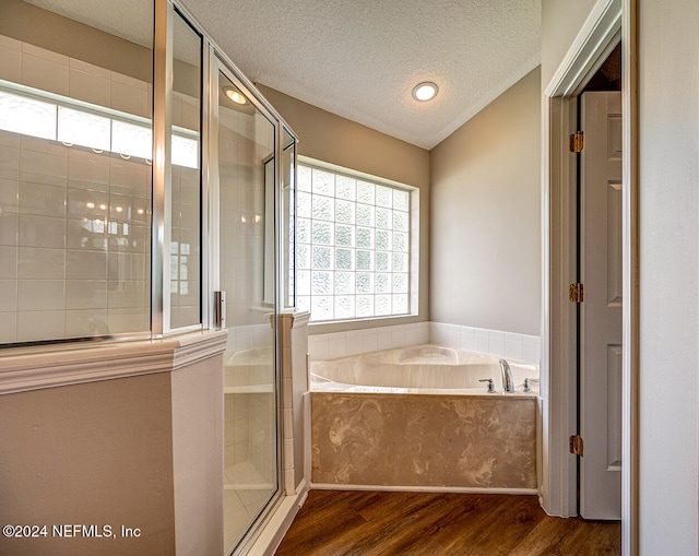 bathroom with lofted ceiling, a textured ceiling, hardwood / wood-style floors, and separate shower and tub