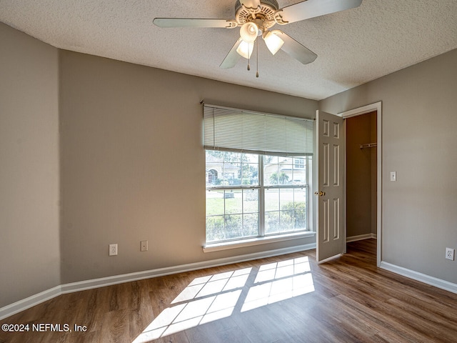 empty room with ceiling fan, hardwood / wood-style flooring, and a textured ceiling