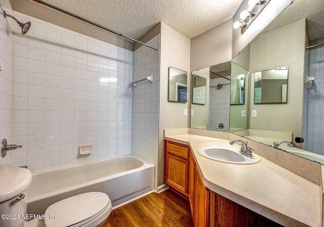 full bathroom featuring tiled shower / bath, a textured ceiling, wood-type flooring, toilet, and vanity