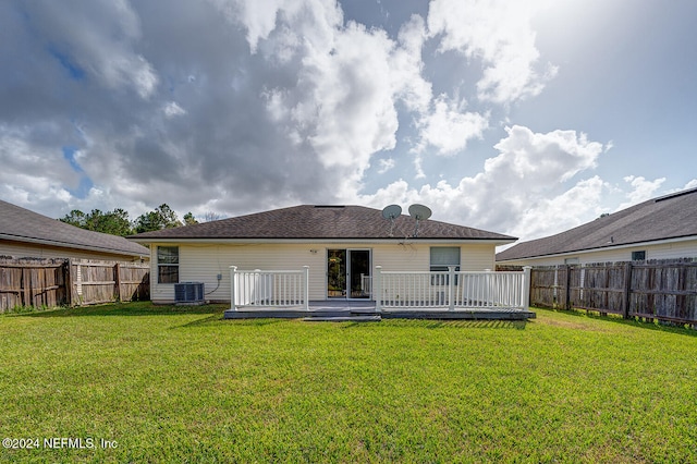 rear view of house featuring central AC, a wooden deck, and a lawn