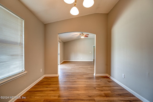 spare room with lofted ceiling, hardwood / wood-style floors, a textured ceiling, and ceiling fan