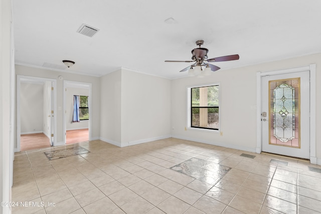 empty room featuring crown molding, light tile patterned floors, and ceiling fan