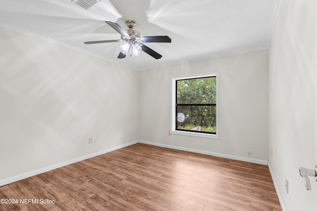 spare room featuring baseboards, visible vents, a ceiling fan, crown molding, and light wood-style floors