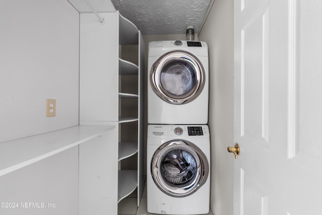 laundry room featuring stacked washer / dryer, laundry area, and a textured ceiling