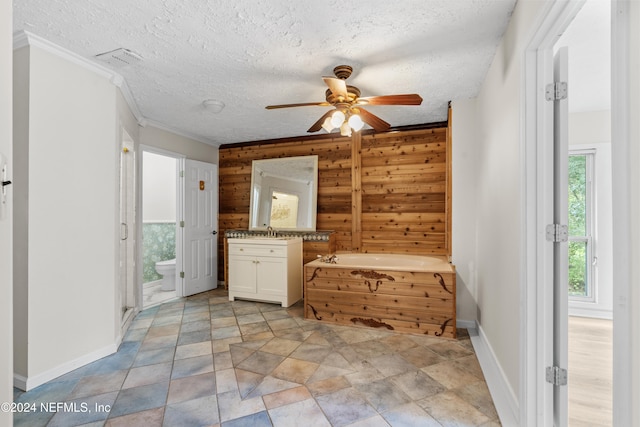 bathroom featuring ceiling fan, toilet, a bath, vanity, and wooden walls