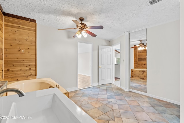 bathroom featuring a textured ceiling, wooden walls, and a bathtub