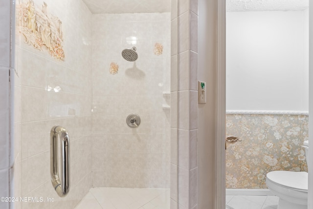 bathroom featuring tile patterned floors, a tile shower, a textured ceiling, and toilet