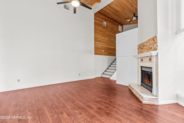 unfurnished living room featuring stairs, wood finished floors, a tile fireplace, and a ceiling fan