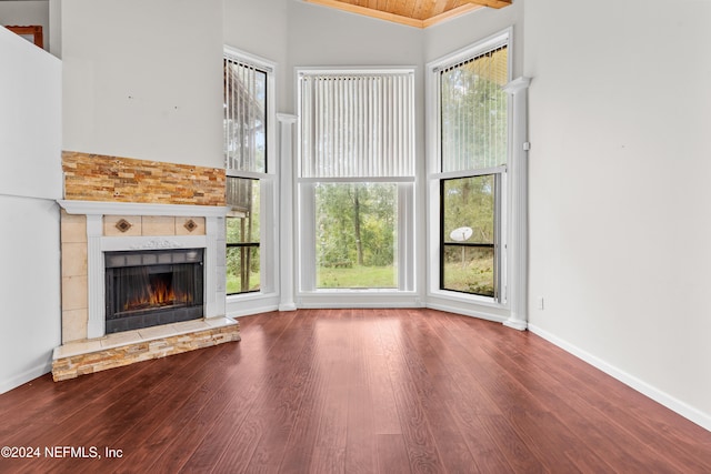 unfurnished living room with high vaulted ceiling, wood-type flooring, plenty of natural light, and a fireplace