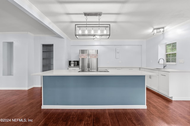 kitchen featuring dark wood-type flooring, ornamental molding, sink, pendant lighting, and white cabinetry