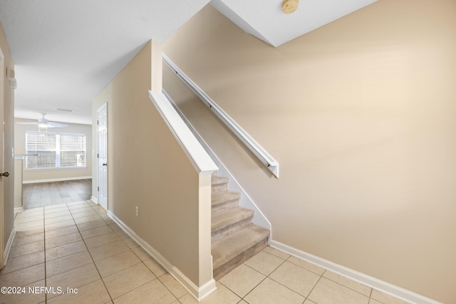 stairway with tile patterned floors and ceiling fan