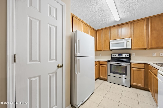 kitchen with sink, white appliances, a textured ceiling, and light tile patterned floors