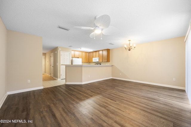 unfurnished living room with ceiling fan with notable chandelier, a textured ceiling, and light hardwood / wood-style flooring