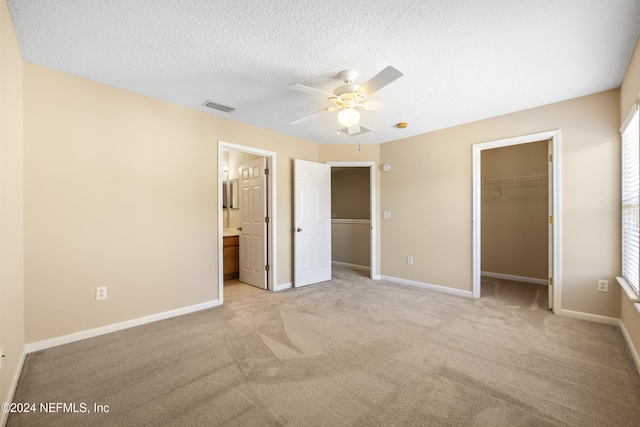 unfurnished bedroom with ceiling fan, a closet, ensuite bathroom, and light carpet