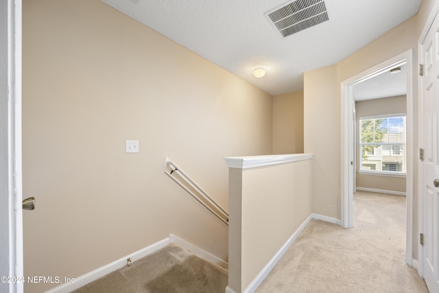 hallway featuring light carpet and a textured ceiling