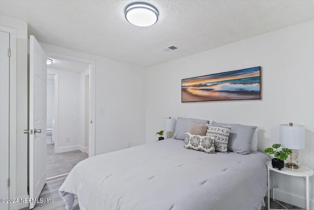 bedroom featuring light hardwood / wood-style flooring and a textured ceiling