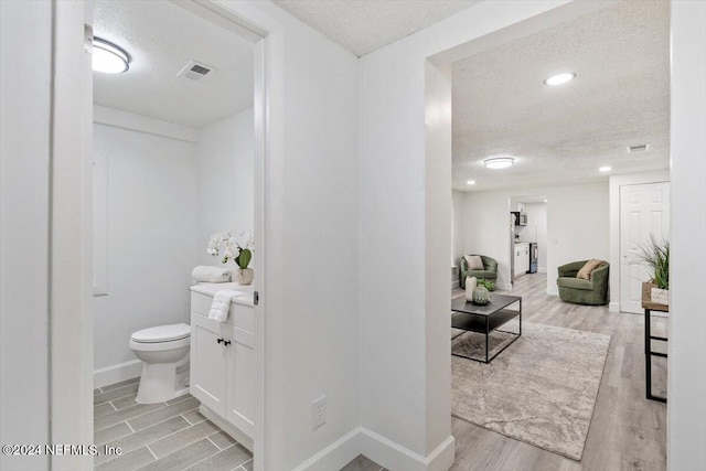 bathroom featuring a textured ceiling, wood-type flooring, and toilet