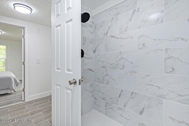 bathroom featuring a textured ceiling and tiled shower