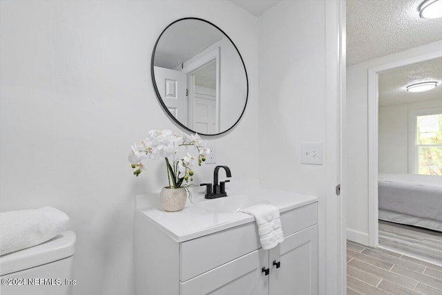 bathroom with vanity, a textured ceiling, hardwood / wood-style flooring, and toilet