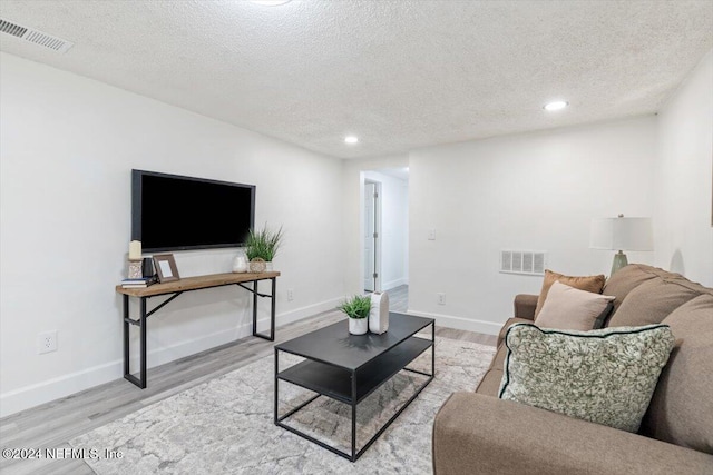 living room featuring a textured ceiling and light wood-type flooring