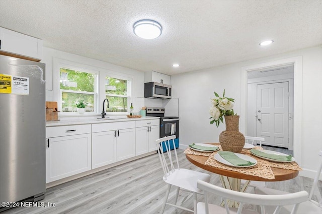 kitchen featuring sink, appliances with stainless steel finishes, a textured ceiling, and white cabinetry